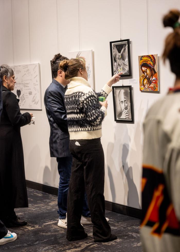 people looking at art hanging on a gallery wall