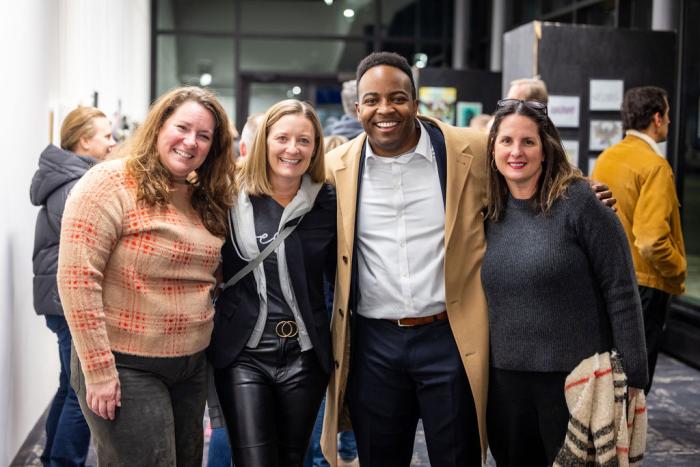 four people stand smiling facing the camera