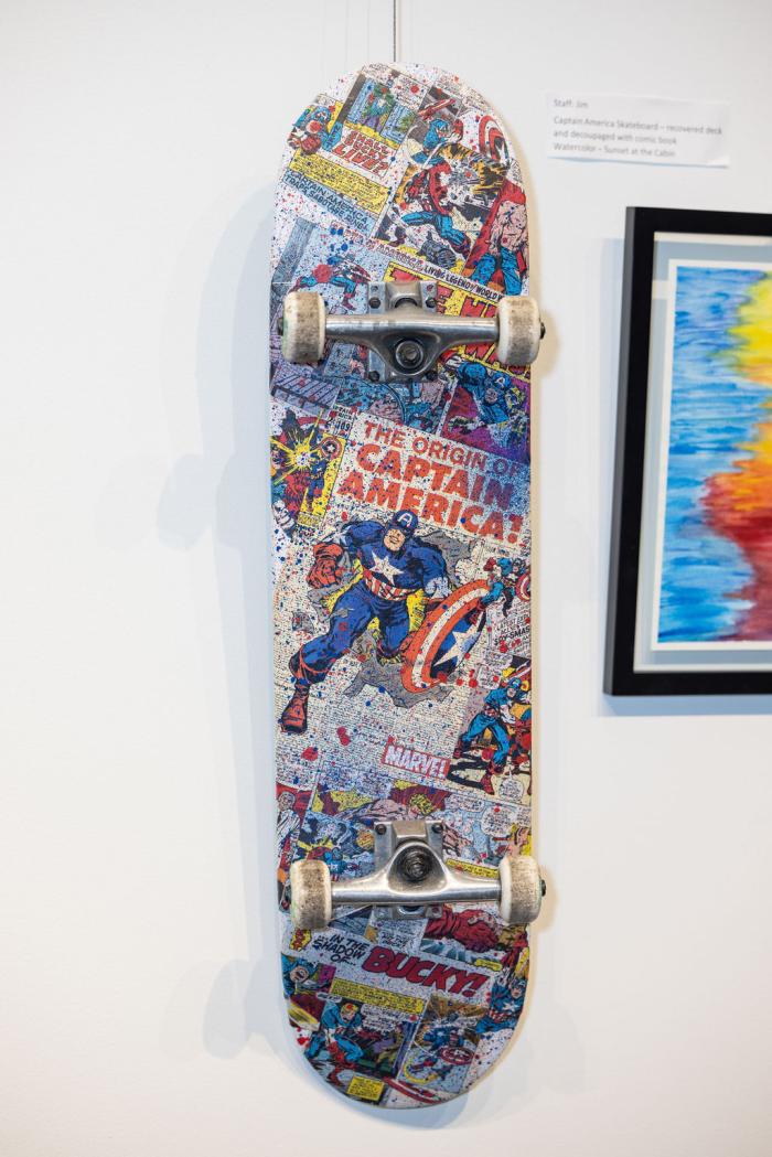 skateboard hanging on wall with captain america themed artwork