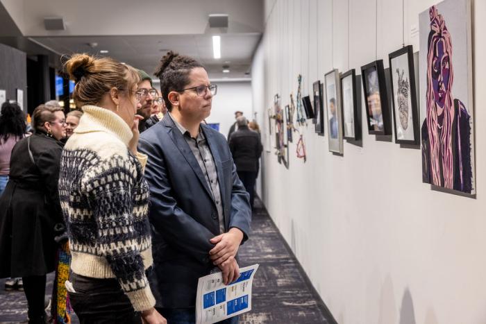 two people observe art on a gallery wall